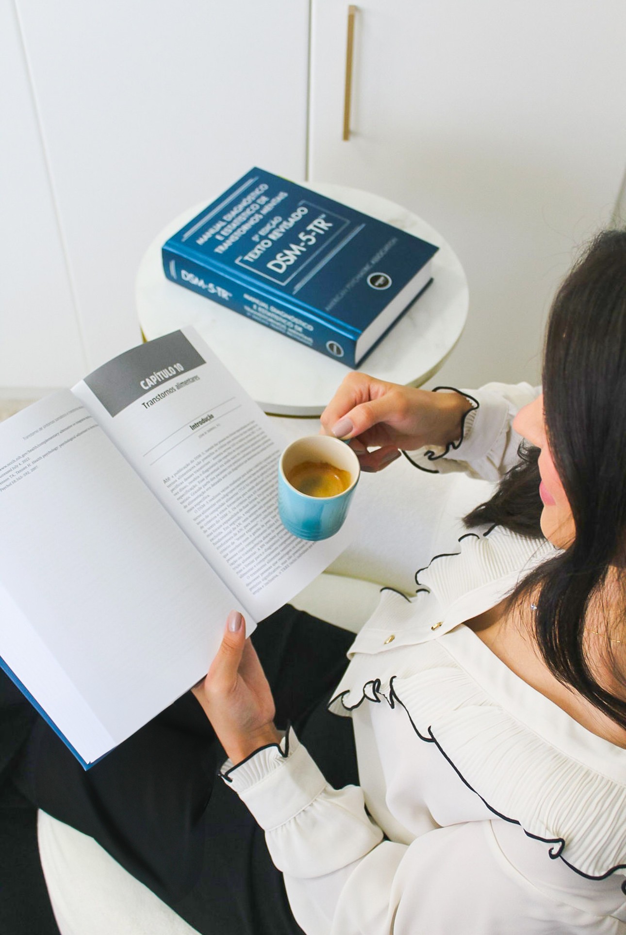 Fernanda Lisboa estudando literatura clínica sobre transtornos alimentares, com o DSM-5-TR ao lado